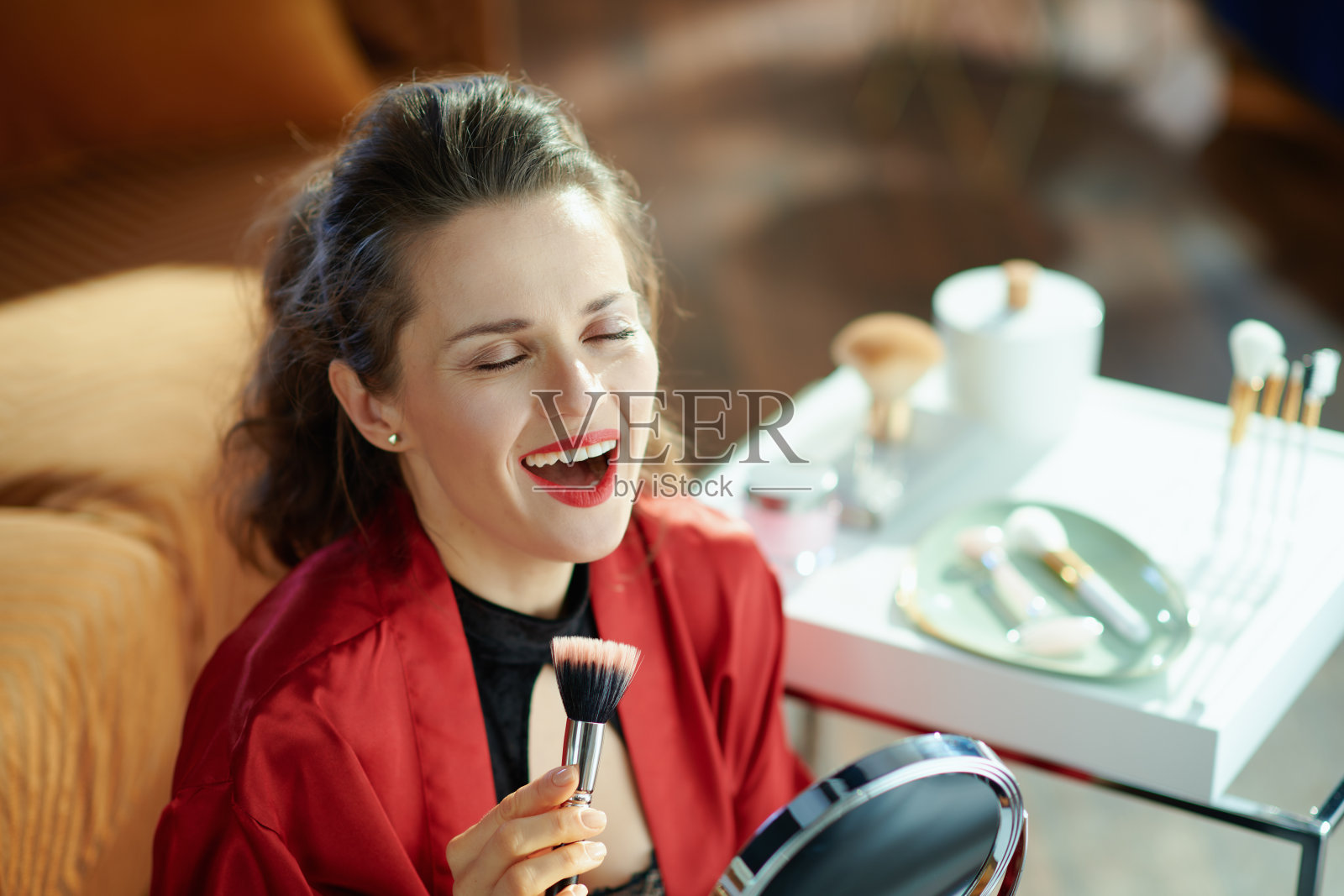 微笑新潮的家庭主妇用化妆刷镜子唱歌照片摄影图片