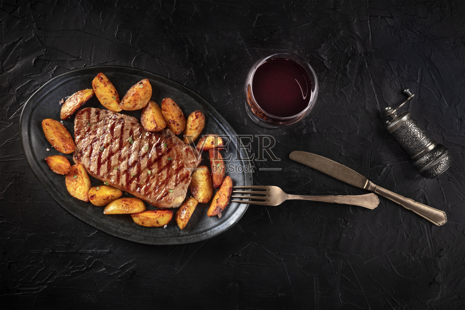烤牛排，烤土豆角和红酒，从顶部拍摄的黑色背景照片摄影图片