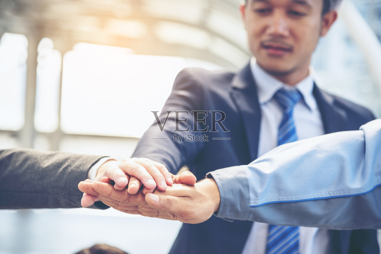 一起团队合作的概念。一群多元化的人在空中击掌，欢迎标签团队的力量。多民族的人一起工作。在业务团队的成功中自愿合作照片摄影图片