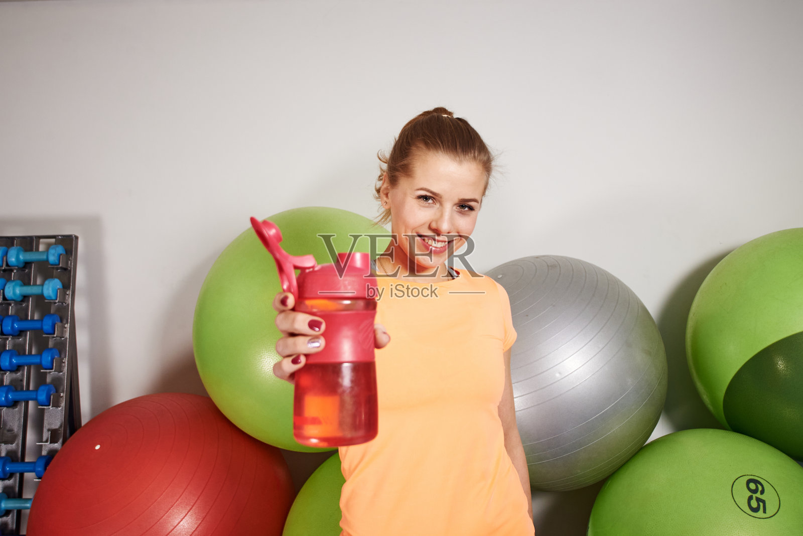 苗条的运动员年轻女子在健身俱乐部运动服装与水瓶。照片摄影图片