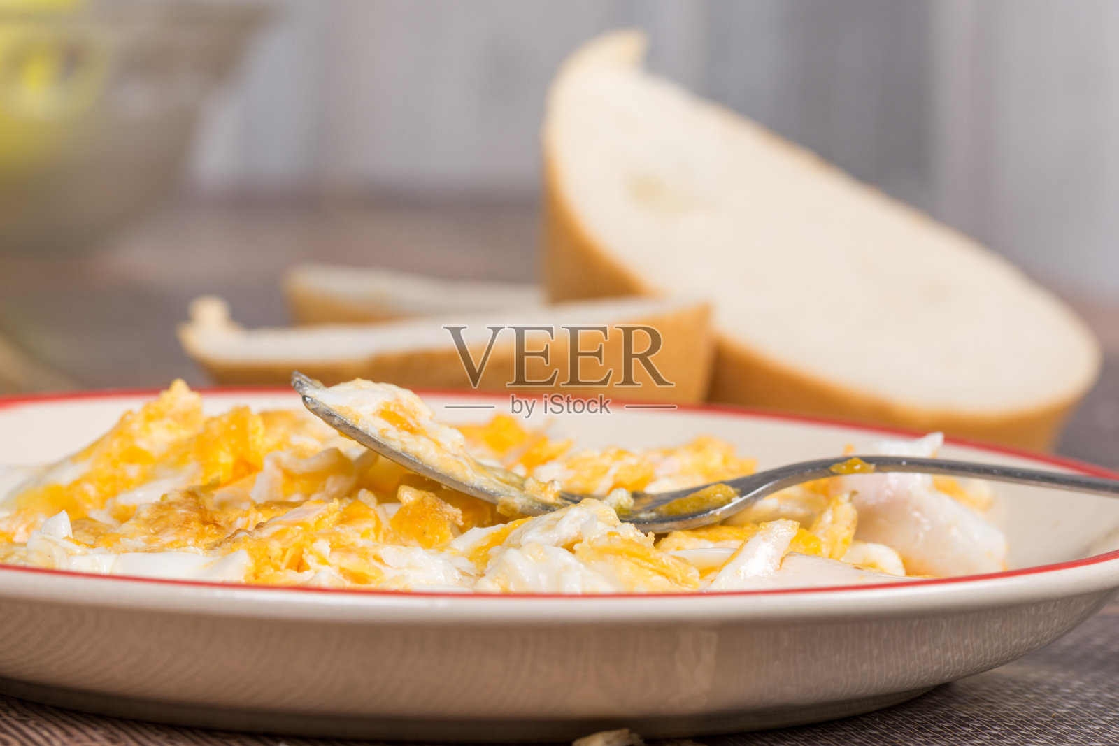 煎蛋在盘子里，以叉子和面包为背景照片摄影图片