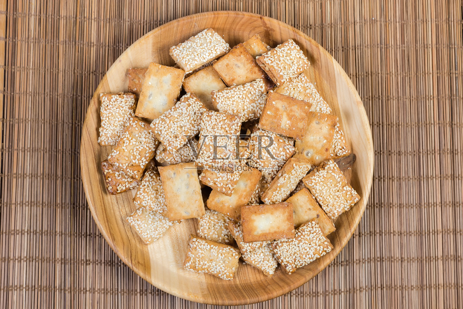 薄芝麻饼放在竹席上的木盘上照片摄影图片