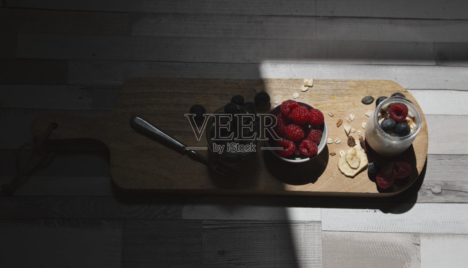 鸟瞰图木制砧板与各种森林浆果和天然酸奶。蓝莓和树莓。照片摄影图片