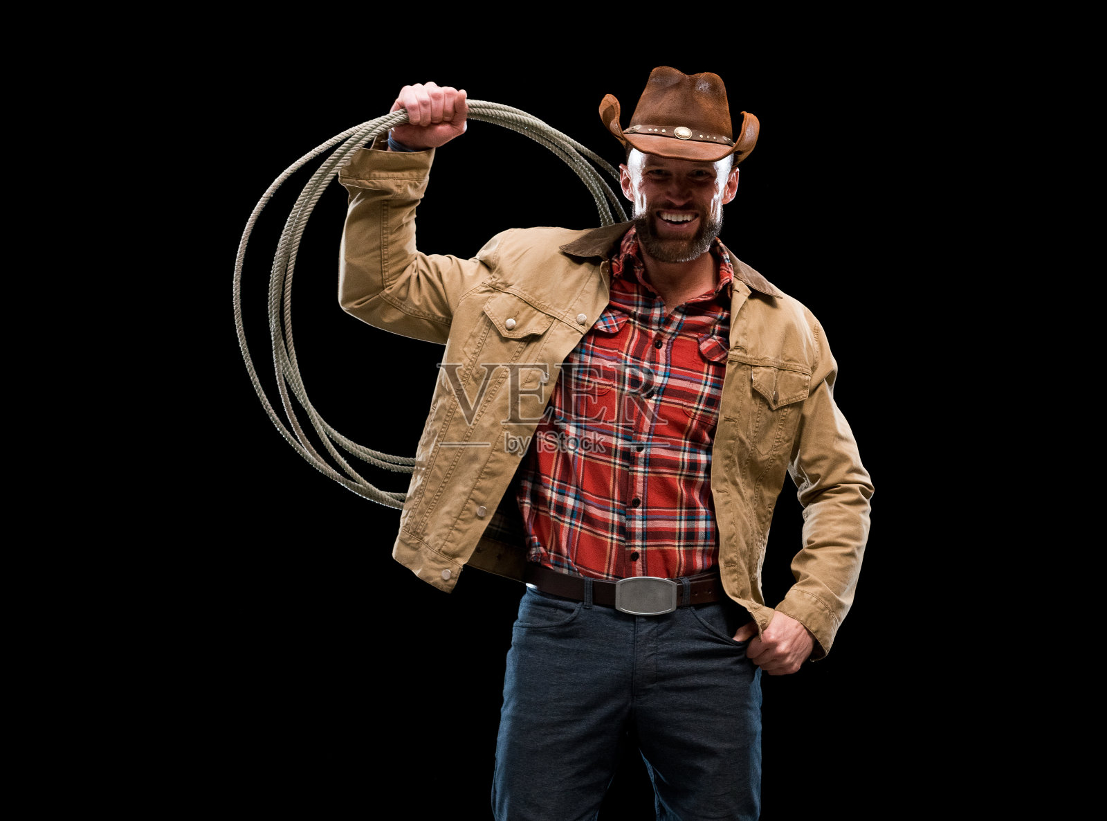 白人年轻男性牛仔身穿衬衫站在黑色背景前，手持套索，使用绳索照片摄影图片