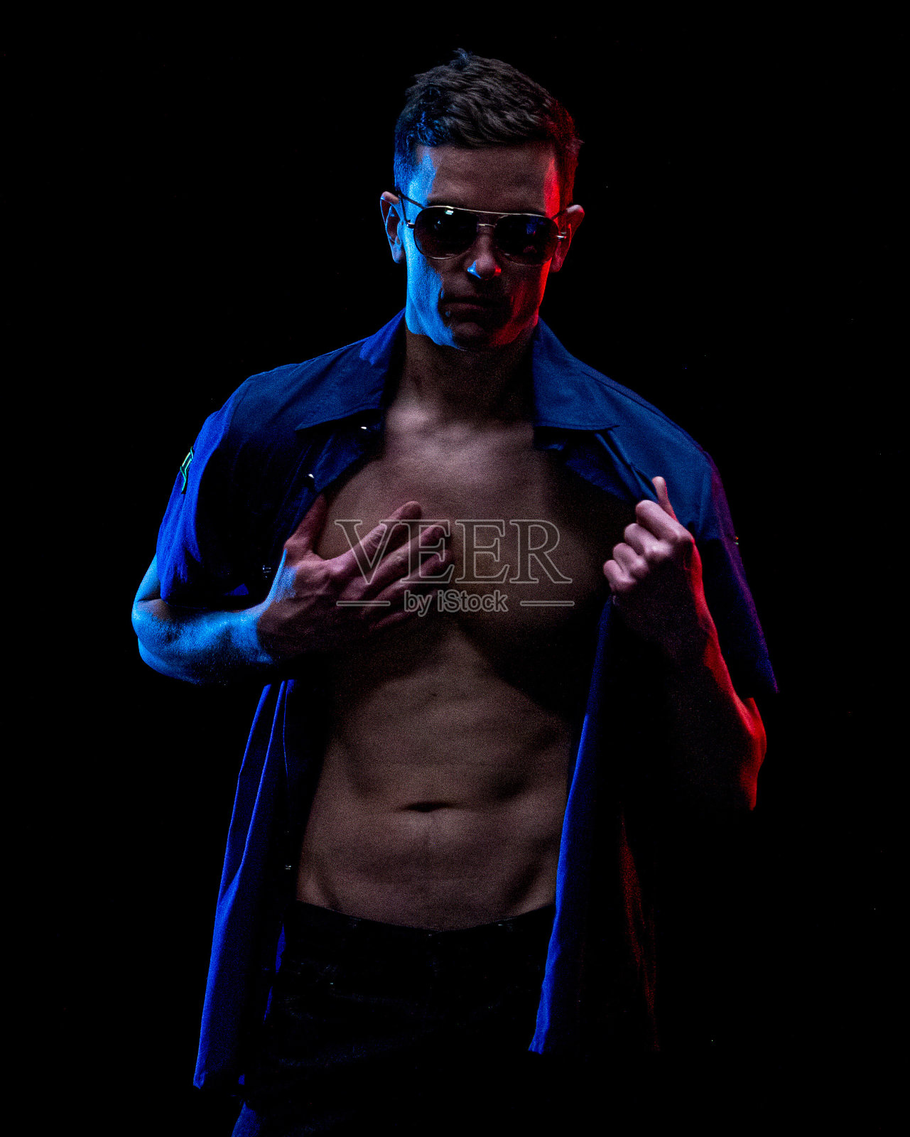 白人年轻男脱衣舞娘穿着裤子站在黑色背景前照片摄影图片