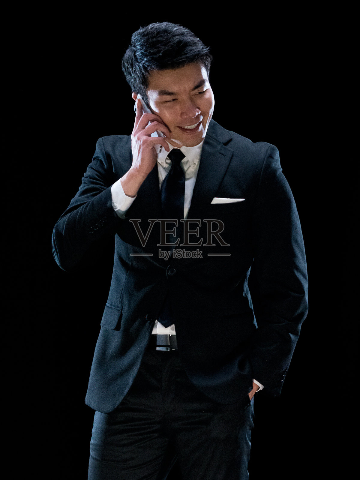 黑色背景前的华裔男性商人穿着商务服，使用智能手机照片摄影图片