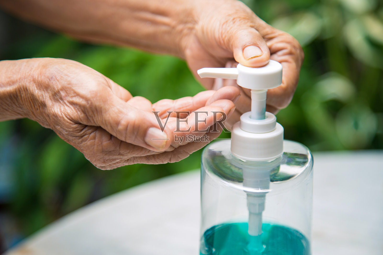 亚洲女性用瓶装酒精消毒液洗手，以防止感染Covid-19病毒照片摄影图片