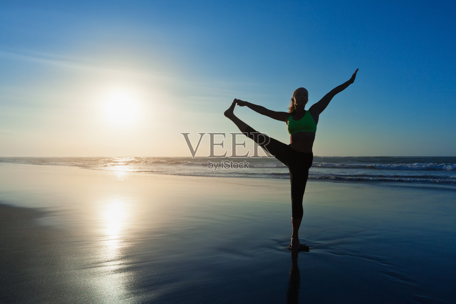 女人的剪影伸展瑜伽姿势在日落海滩照片摄影图片