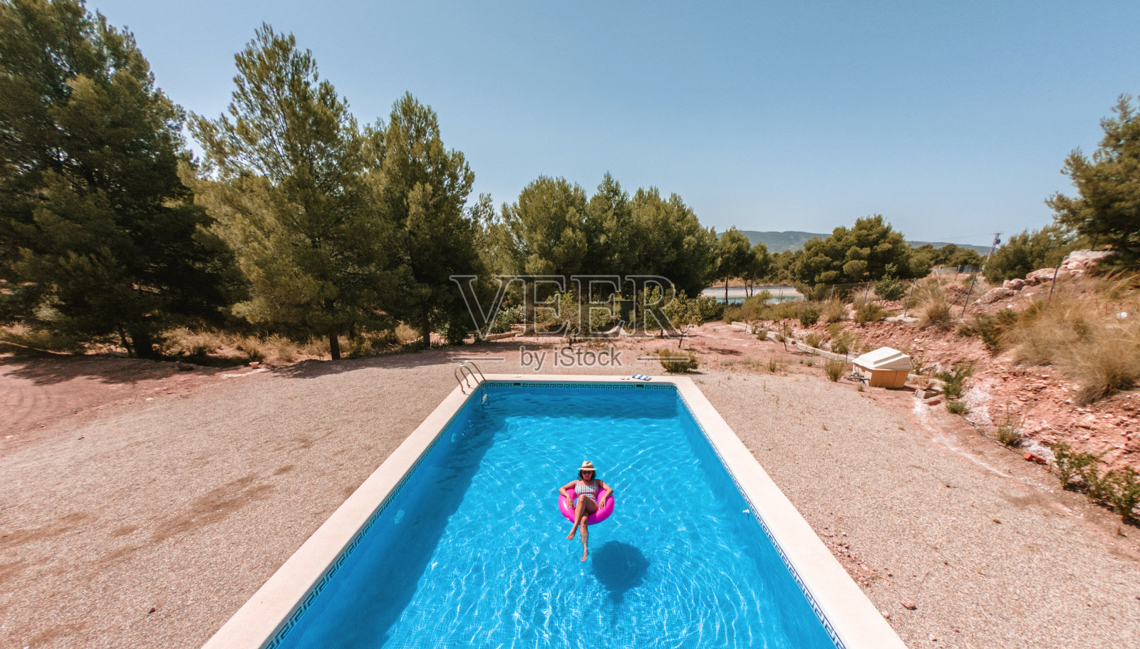 小女孩穿着泳衣，帽子上飘着粉色的甜甜圈。照片摄影图片