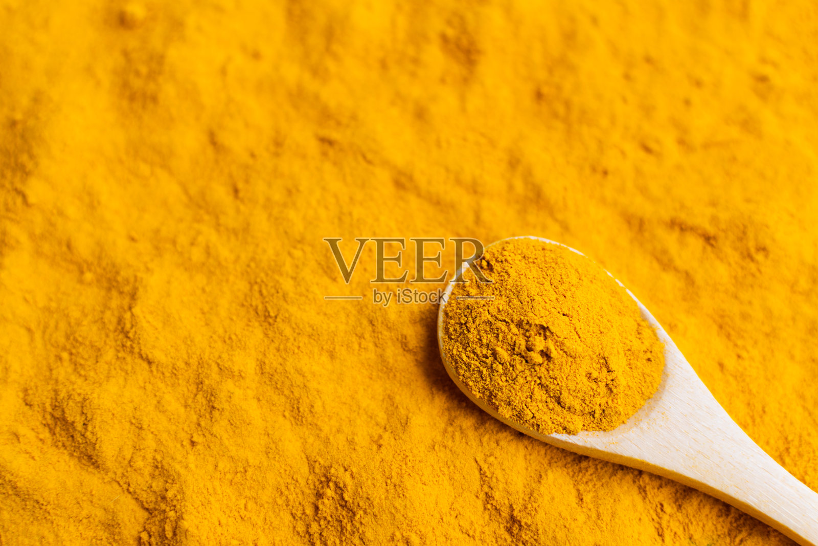 特写姜黄粉在木勺分散姜黄。照片摄影图片