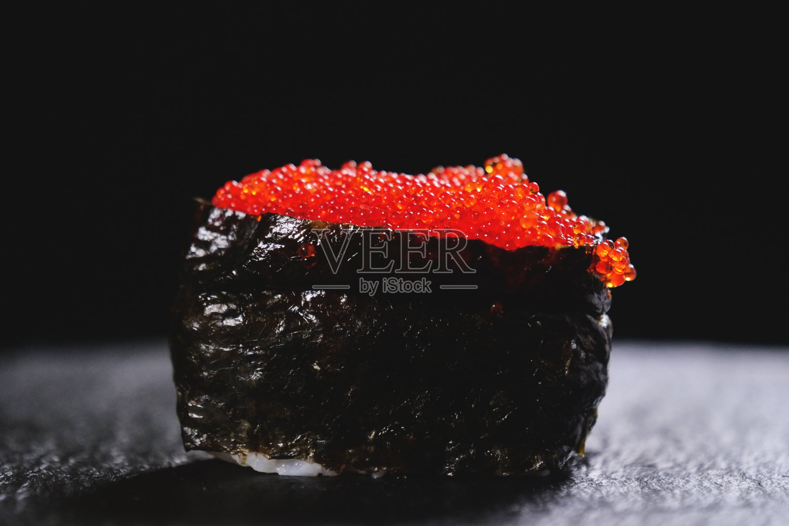 寿司，生鱼片，浦城和夜拍的微距镜头。这是一道典型的日本菜，以米饭、鲑鱼或金枪鱼、虾和鱼卵为背景，配以黑色。照片摄影图片