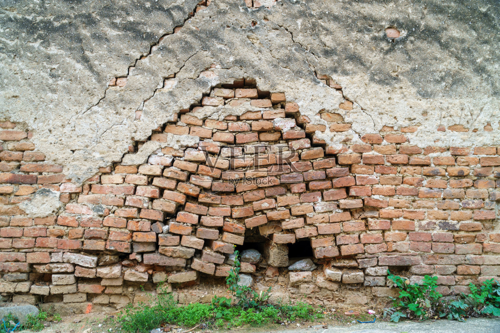破旧的老红砖墙纹理背景随时间的推移而老化。旧砖墙上长满了草照片摄影图片