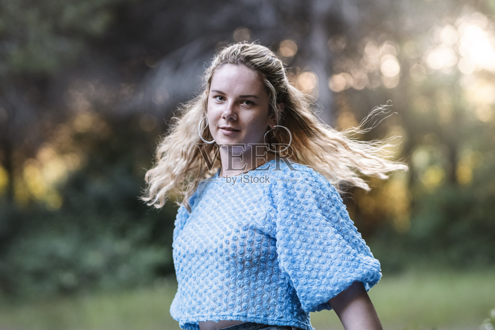 在一个公园里，快乐的年轻女子微笑着看着相机的肖像照片摄影图片