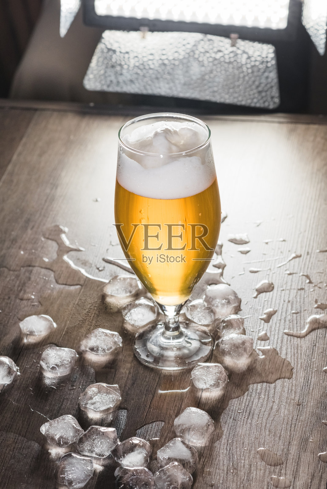 桌上有一杯加冰的淡啤酒。休闲、酒吧和派对的概念照片摄影图片