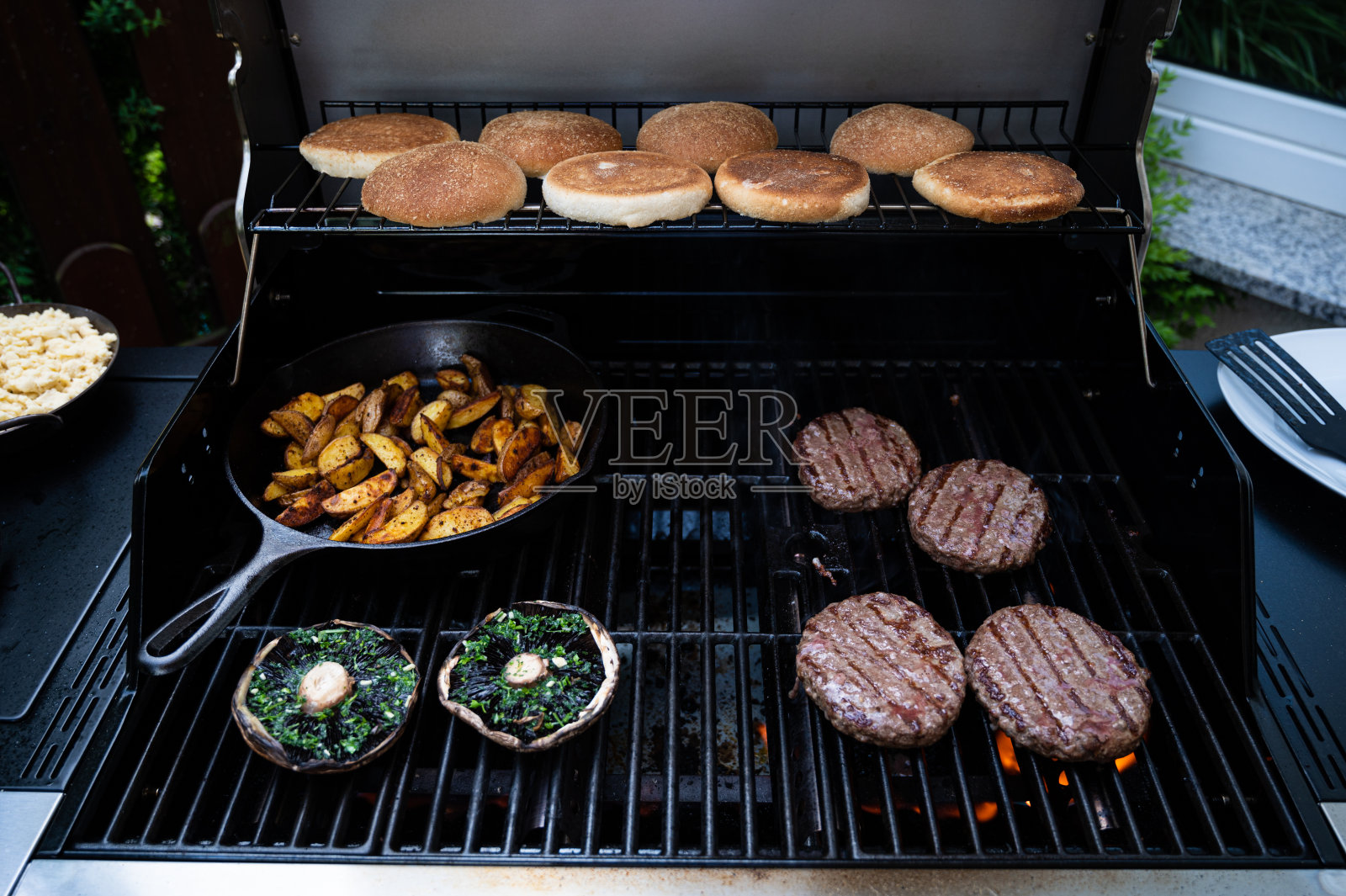 烧烤架上的汉堡，平底锅里的土豆角和巨大的蘑菇照片摄影图片