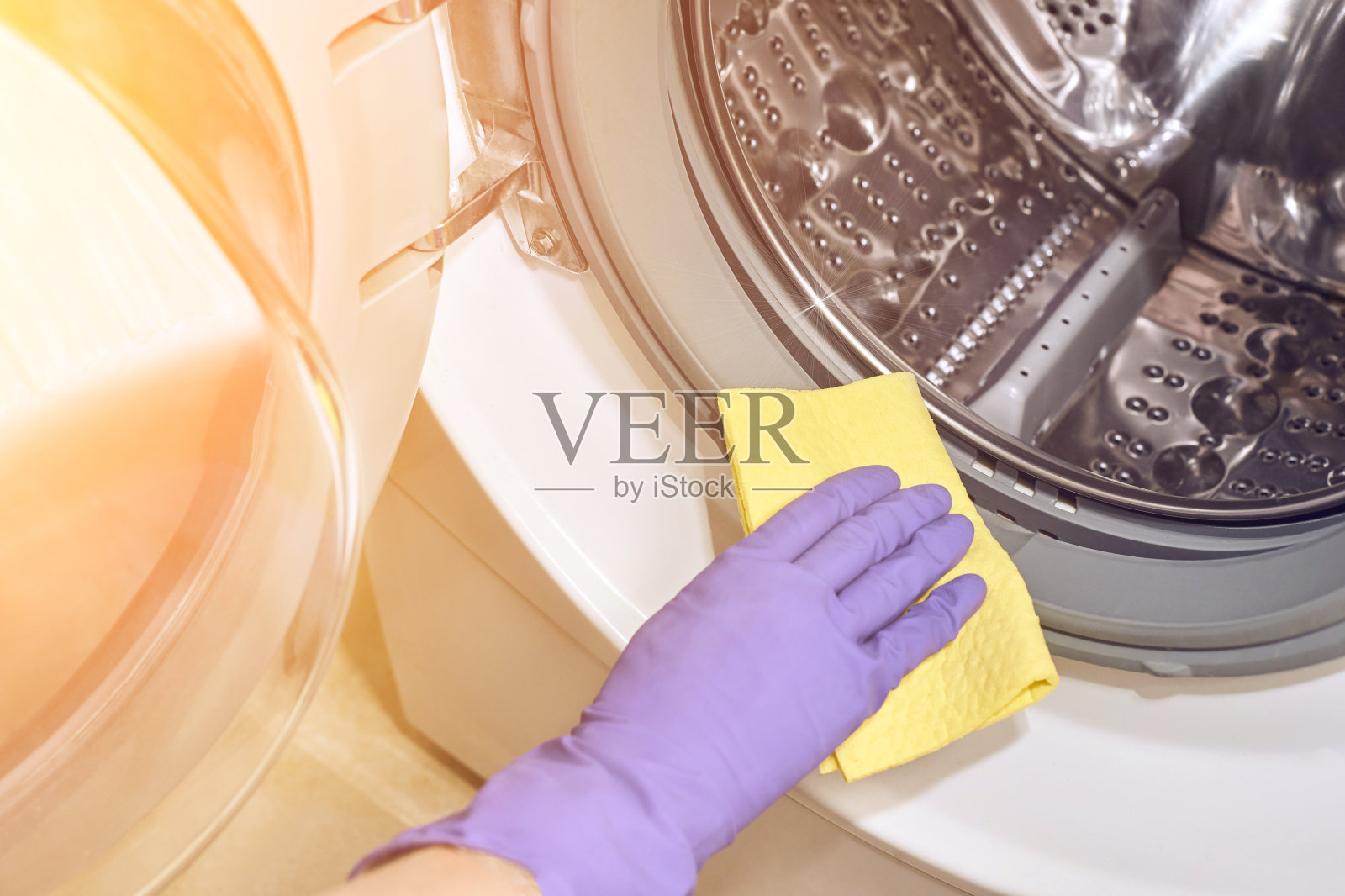 手戴紫色防护手套和抹布。清洁洗衣机照片摄影图片