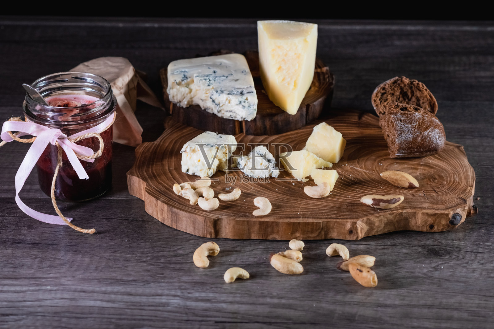 奶酪和面包放在木架上，桌子的背景是黑色的。营养的概念和美丽的服务的食物。照片摄影图片