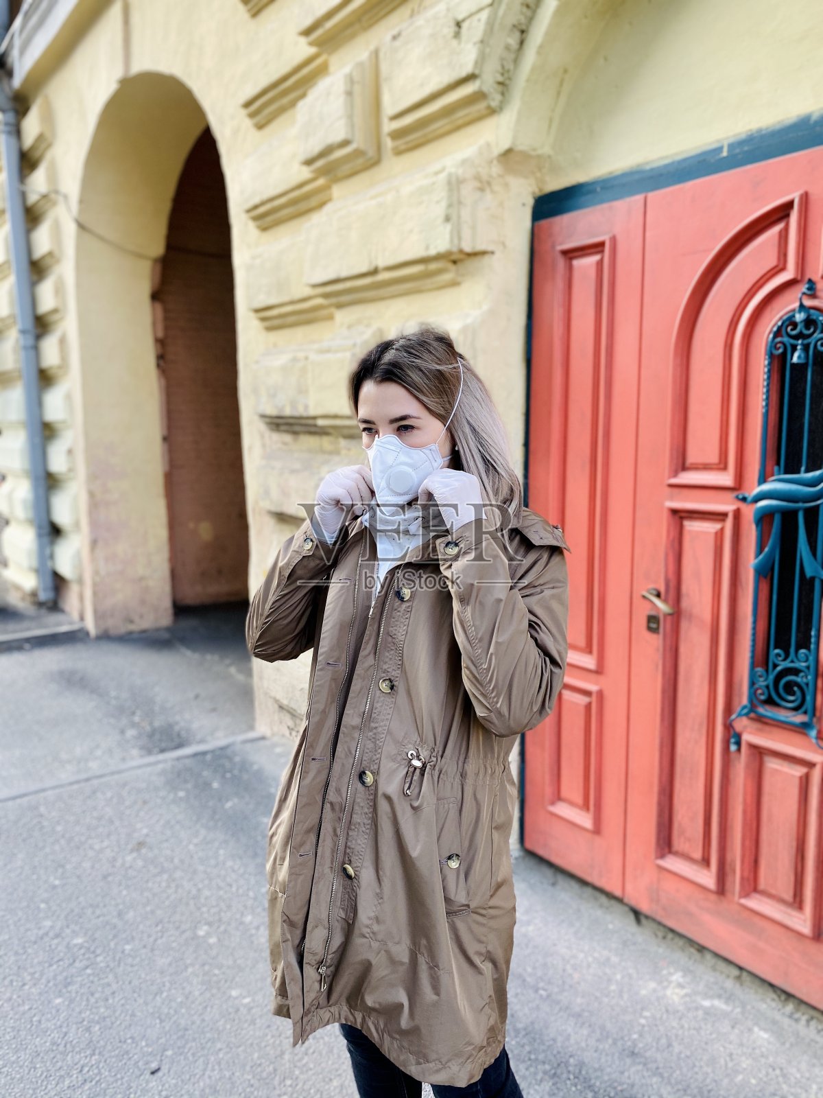 时尚的年轻女子戴着防护口罩和白手套，走在老街上。新型冠状病毒肺炎照片摄影图片