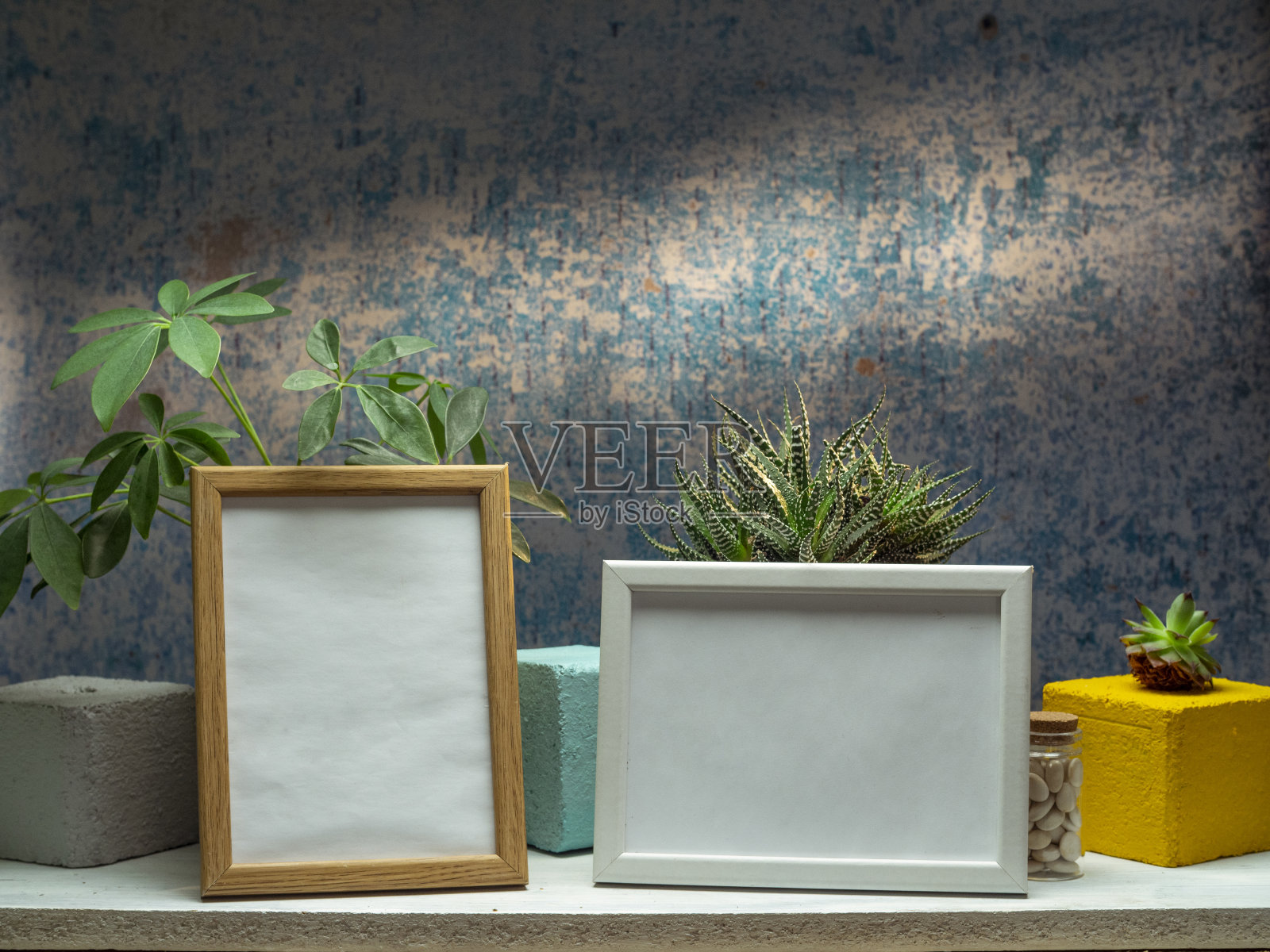 两个相框模型和植物在白色架子上靠旧的蓝色墙壁。照片摄影图片