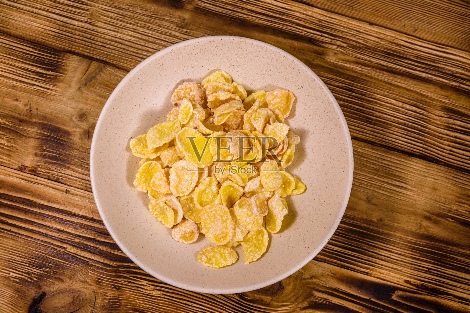 木桌上放有玉米片的陶瓷盘子。健康饮食。俯视图照片摄影图片
