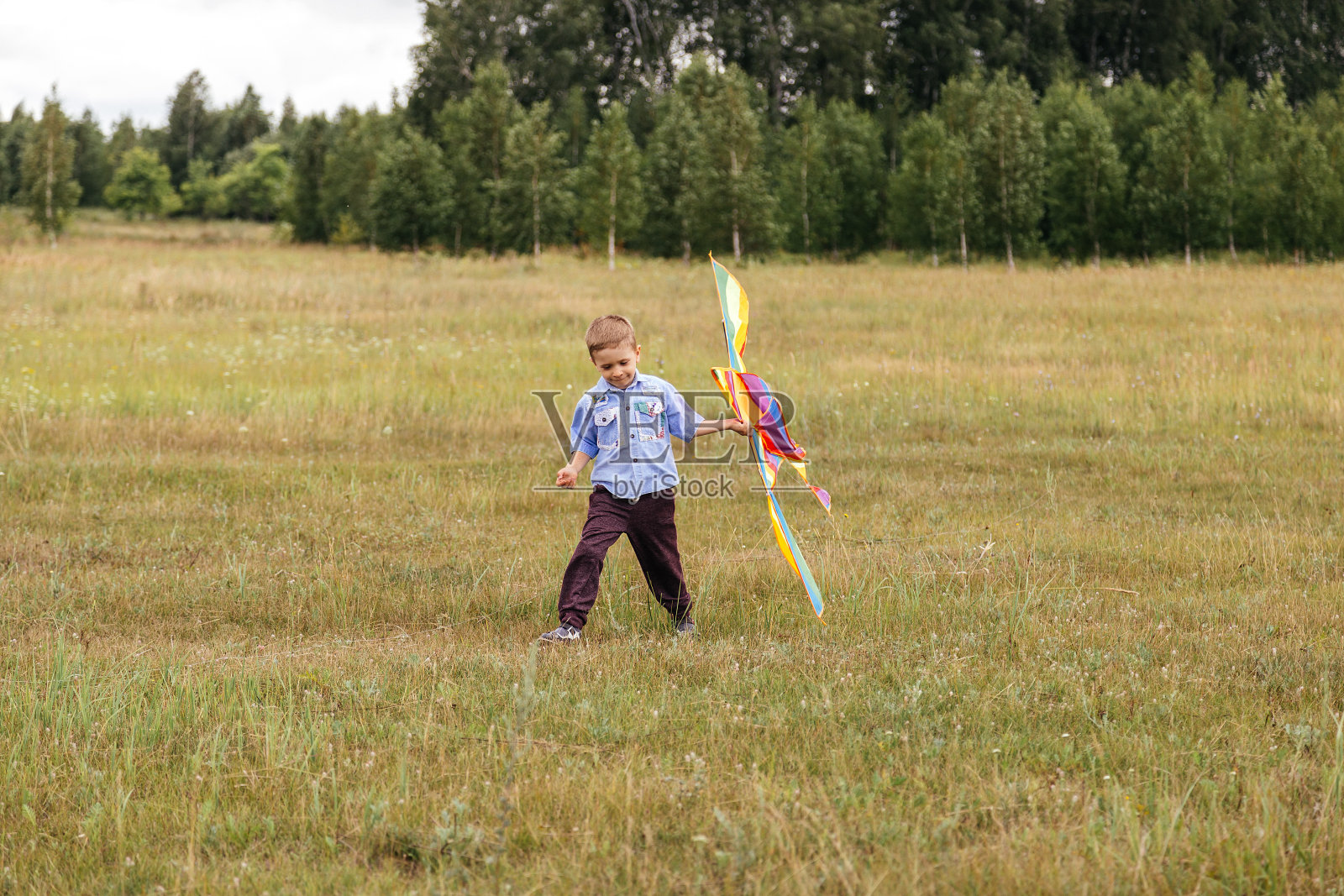 一个男孩在操场上拿着风筝。照片摄影图片