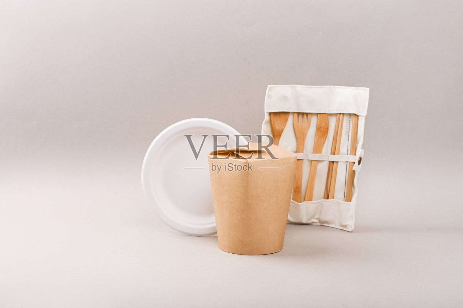 灰色背景的竹木和纸制成的环保一次性餐具。挂勺、叉、刀、盘用。回收的概念。副本的空间。照片摄影图片