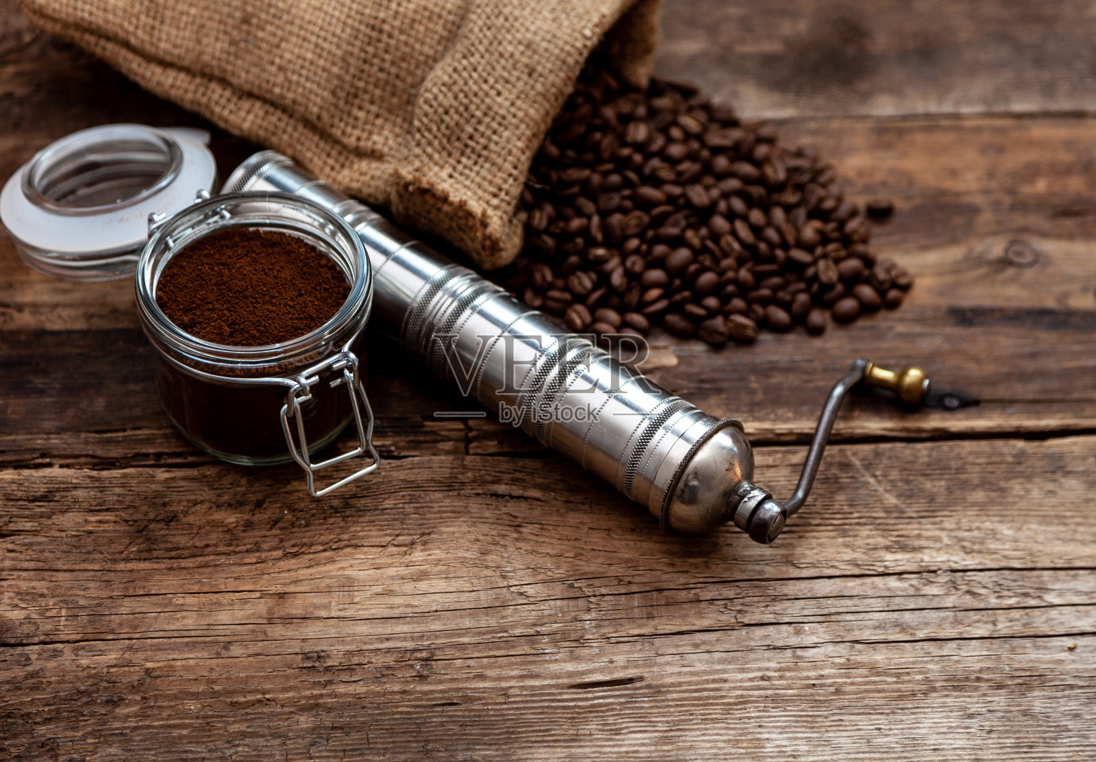 咖啡颗粒从木质背景上的一个罐子里倒出来。咖啡的心情。深色背景，文字位置。厨房的桌子照片摄影图片