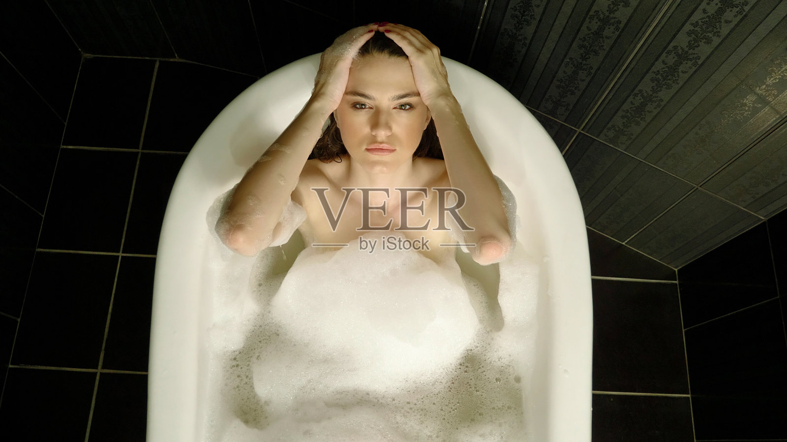 俯视图美丽的年轻女子在洗澡和看着镜头照片摄影图片