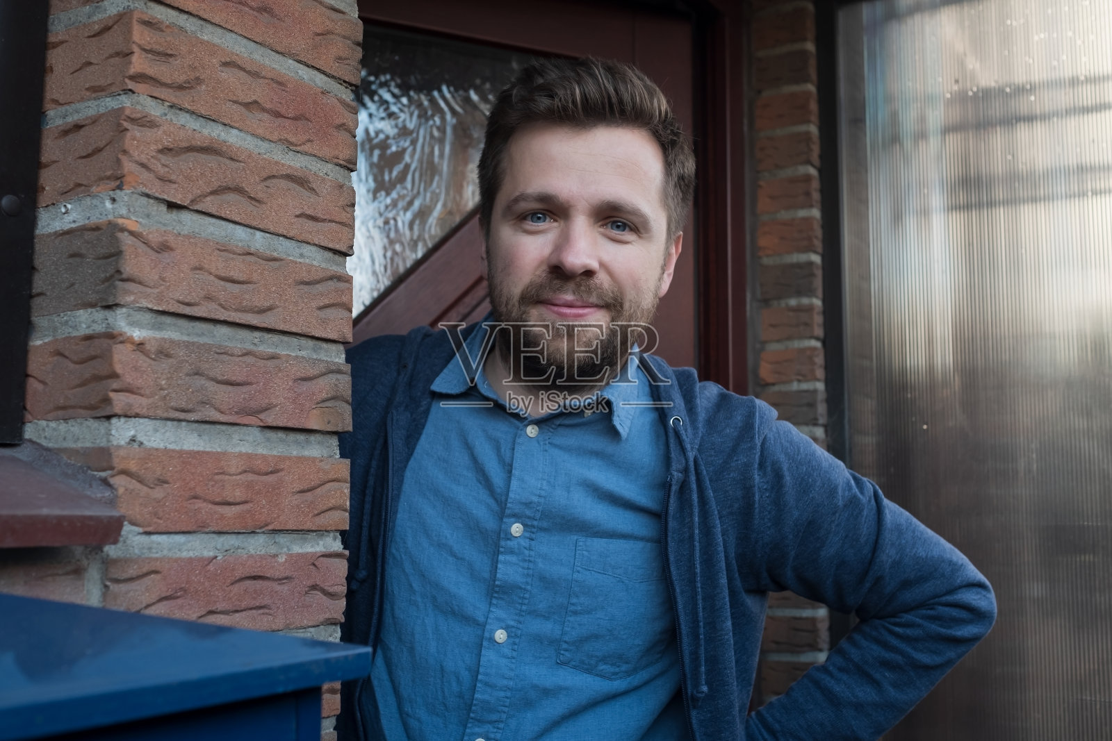 一个微笑着的年轻人正在为他的朋友开门。照片摄影图片