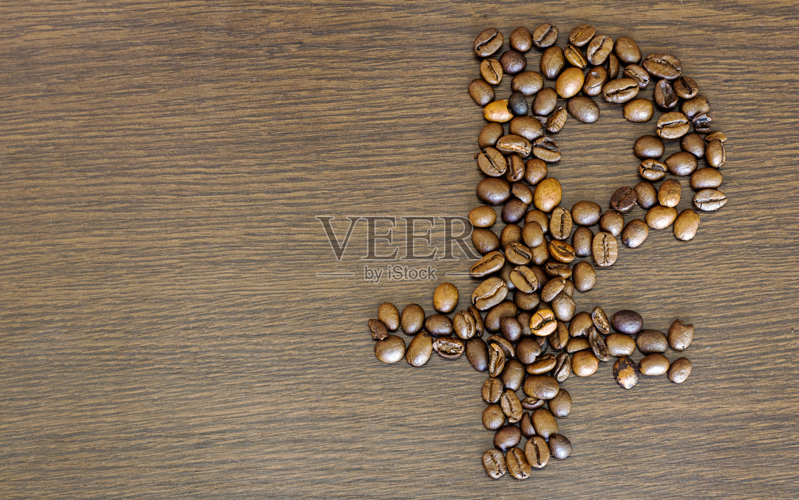 卢布的迹象。俄罗斯卢布用烘烤过的咖啡豆制成的带有较低下划线的俄罗斯卢布标志。谷物躺在浅色的木质纹理台面上。照片摄影图片