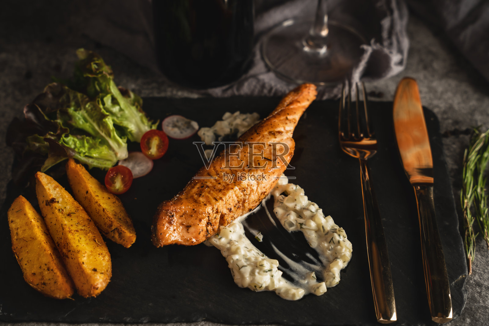 食物背景:照烧三文鱼排配沙拉酱，石盘上，色调较暗照片摄影图片