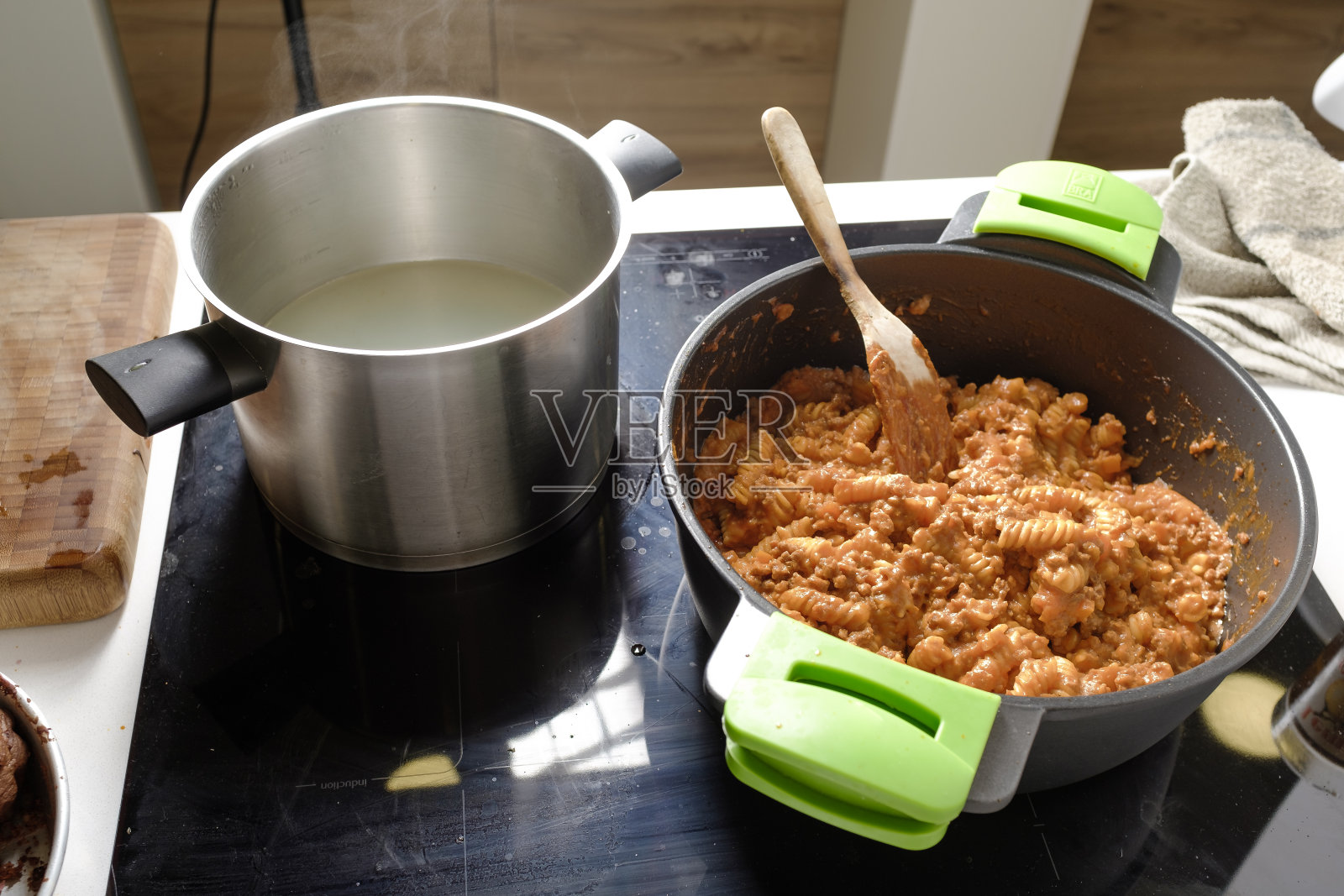 在家庭厨房里，用木勺在黑色平底锅上煮意大利肉酱面照片摄影图片