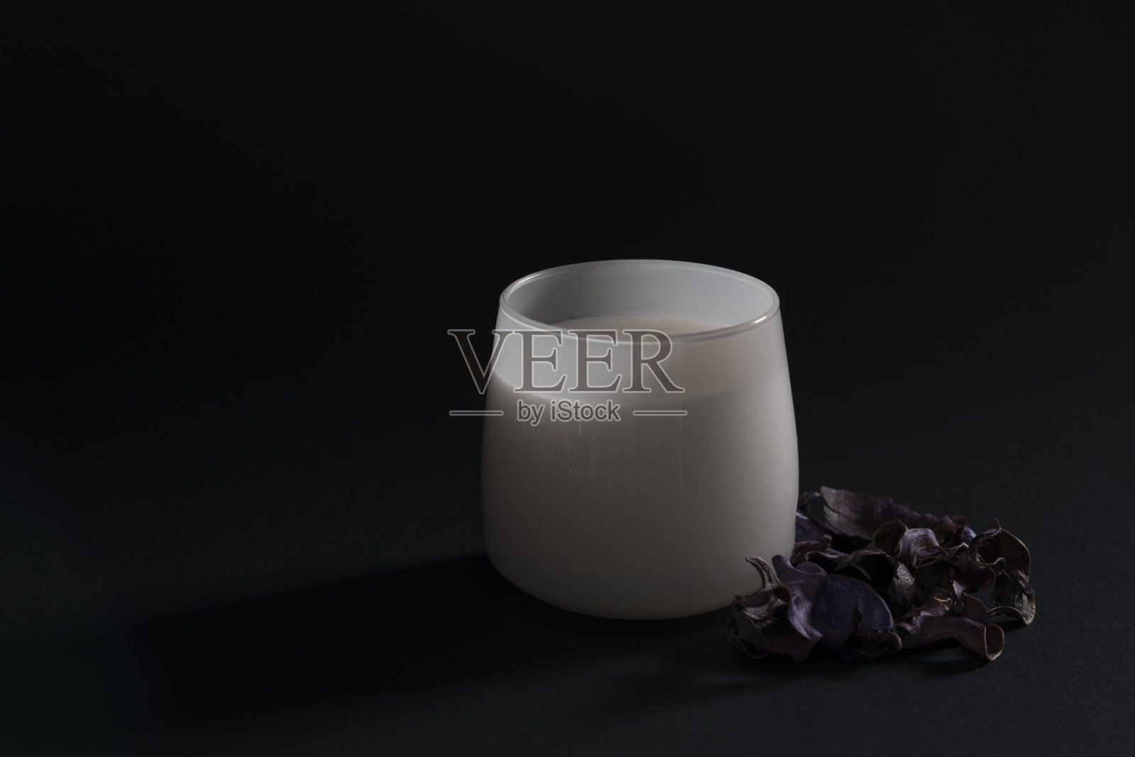 香薰和放松——玻璃杯里的蜡烛和深色背景上的干花。假日或温泉的装饰照片摄影图片