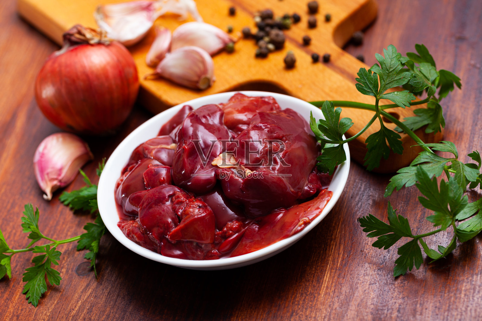 生鸡肝在烹饪前与大蒜和绿色蔬菜照片摄影图片