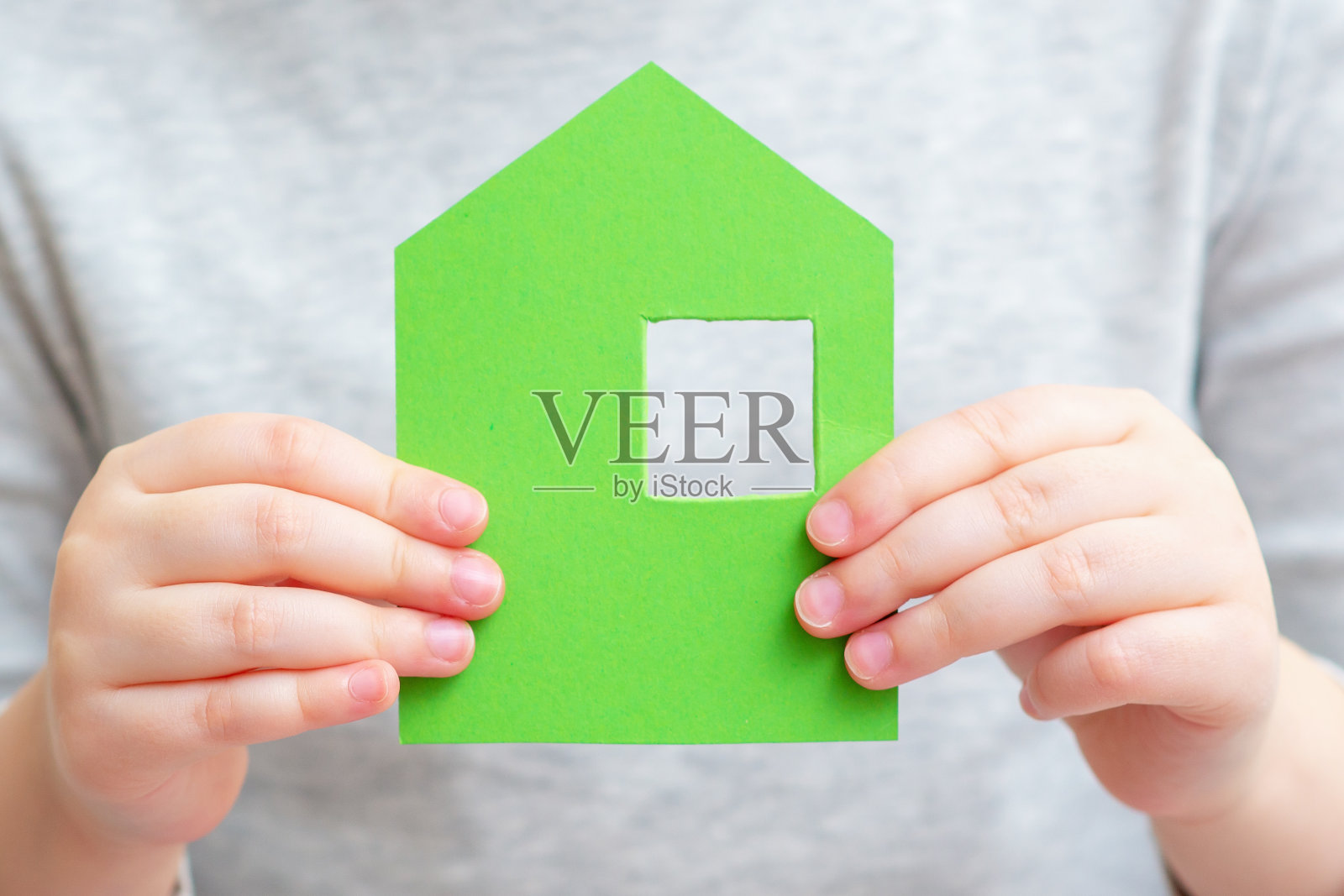 孩子手里拿着小纸房子。照片摄影图片