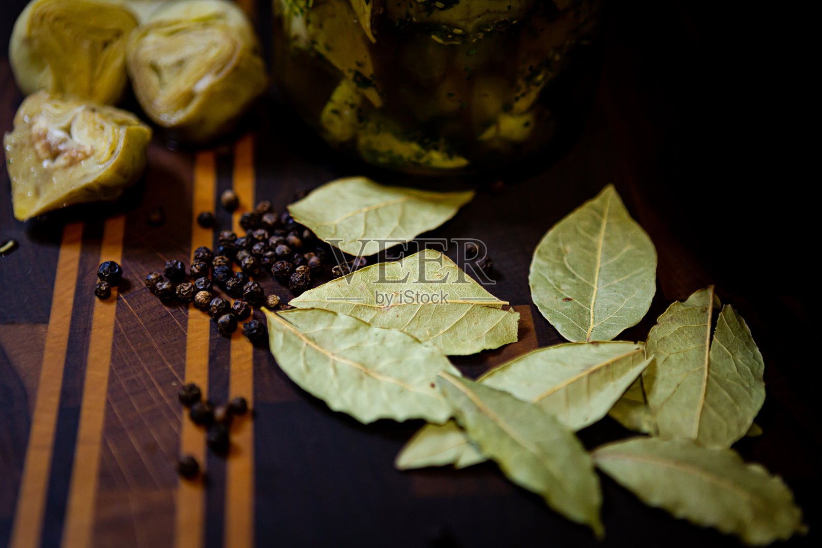 玻璃罐中的洋蓟配黑胡椒，欧芹，大蒜和月桂，各种香料照片摄影图片