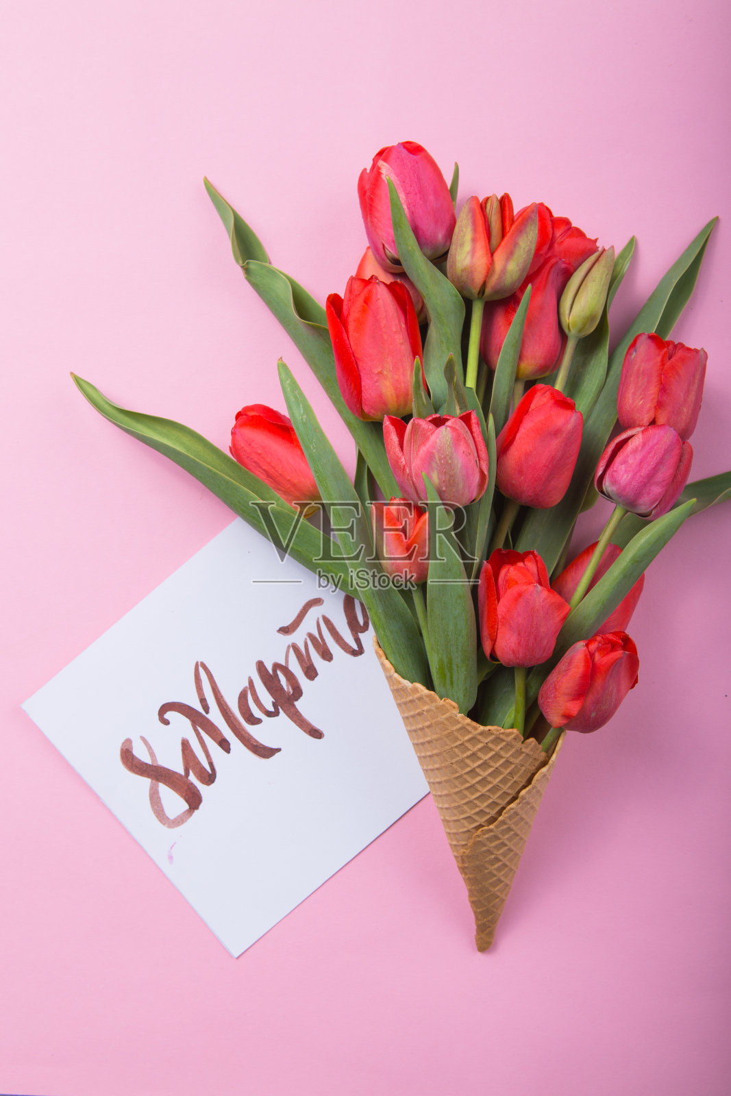 美丽的红色郁金香装在华夫蛋筒里，彩色背景卡片是妇女节。鲜花礼物的概念。春天的心情照片摄影图片