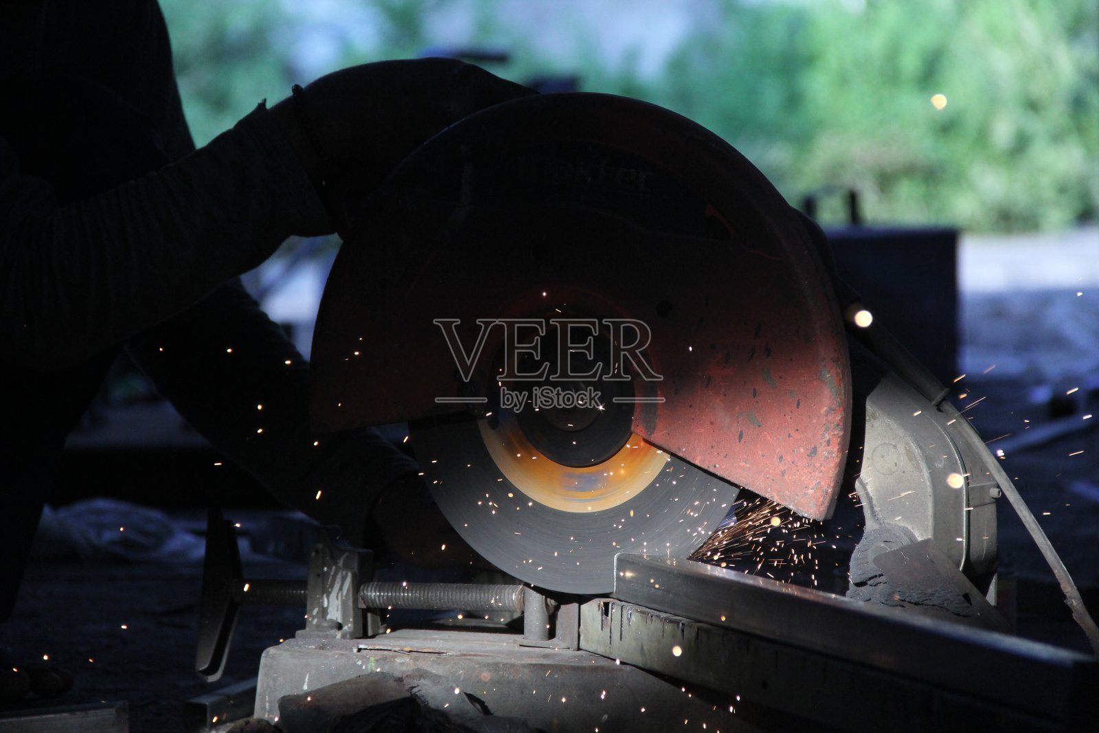 锯铁棒的过程产生的火花创造了美丽的剪影场景。照片摄影图片
