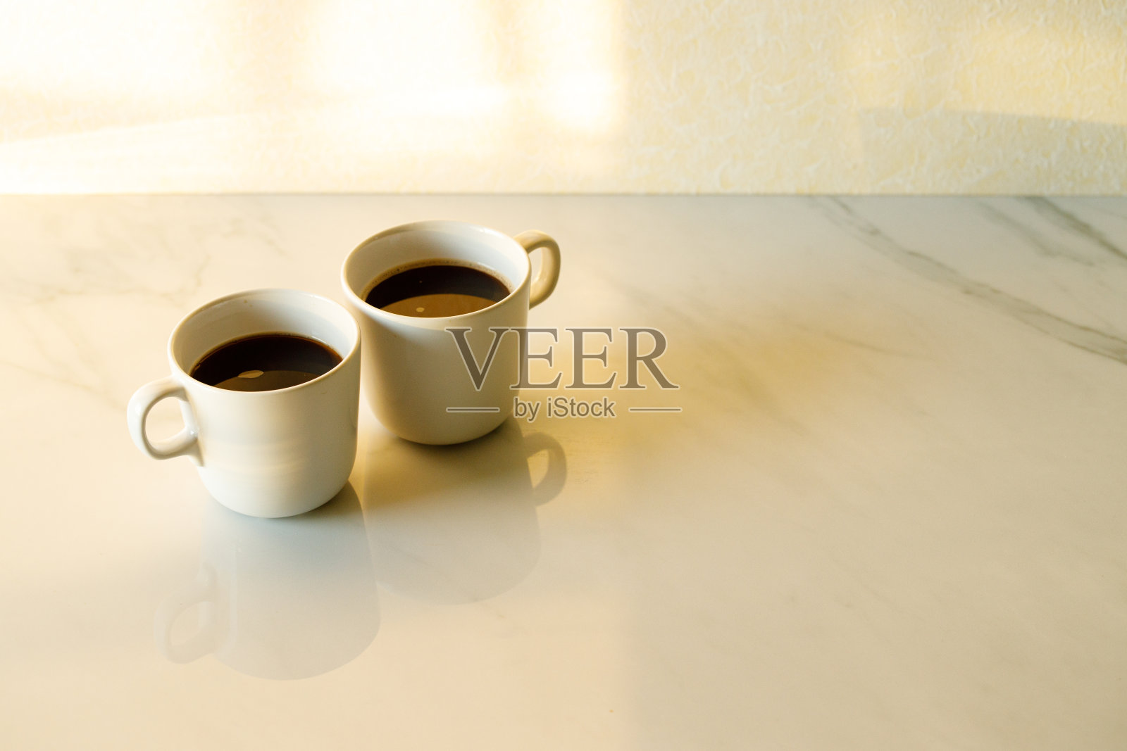 晨光中，白色大理石桌上放着几杯咖啡照片摄影图片