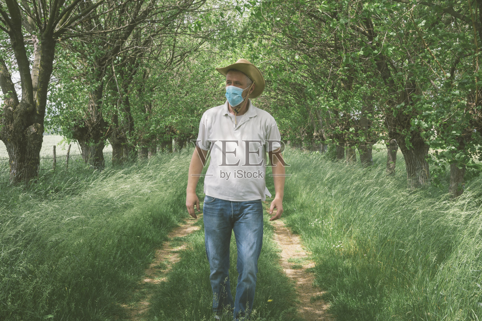 成年男子在春天的大自然中外出时，脸上戴着防护口罩，以防止病毒感染照片摄影图片