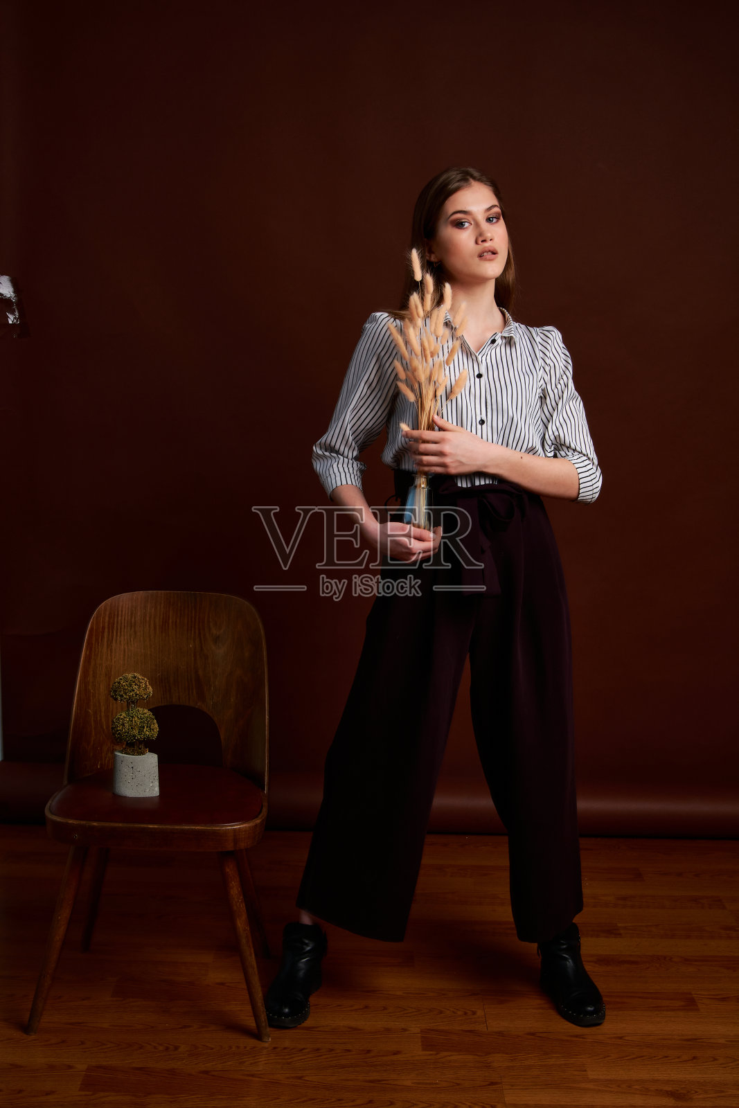 漂亮的年轻女性，穿着经典的套装，黑色的鞋子和灰色的外套。古董椅子。女人的衣服。照片摄影图片