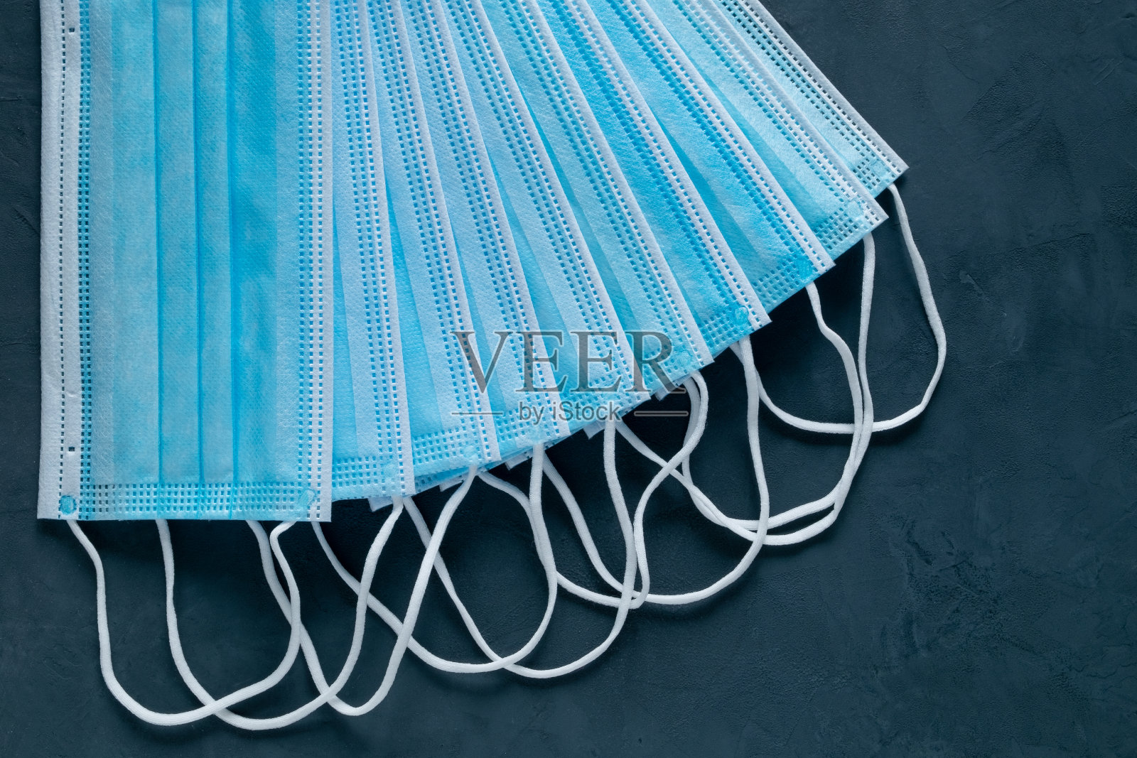 许多医用口罩摆放在一个扇子里，背景是黑色的照片摄影图片