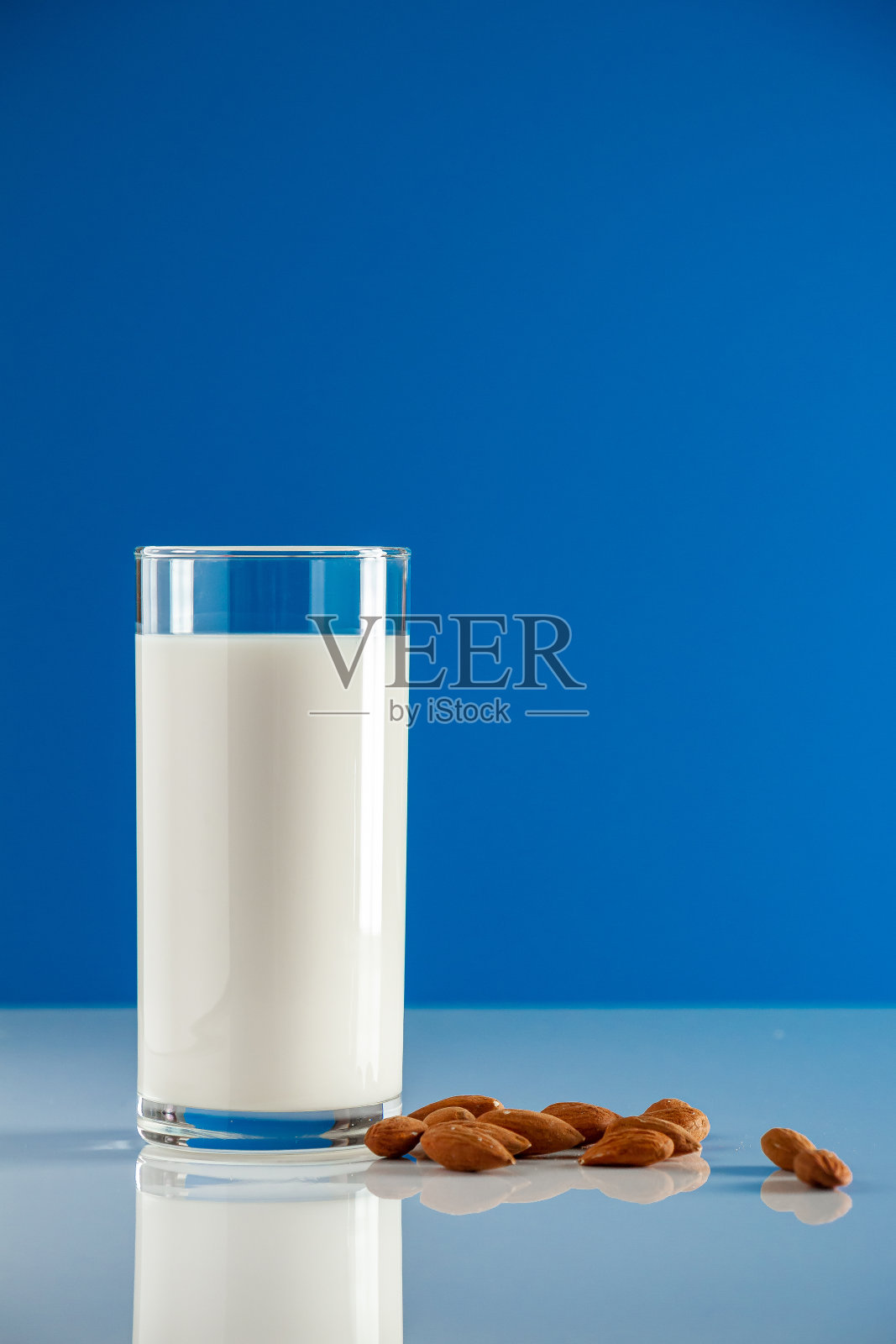 蓝色背景的无谷蛋白杏仁饮料。照片摄影图片
