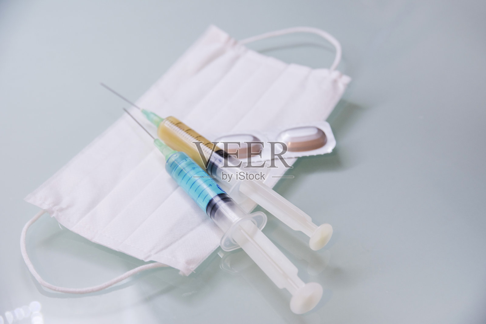 一种防治冠状病毒的概念。药片，注射器，医院里的医用口罩。照片摄影图片