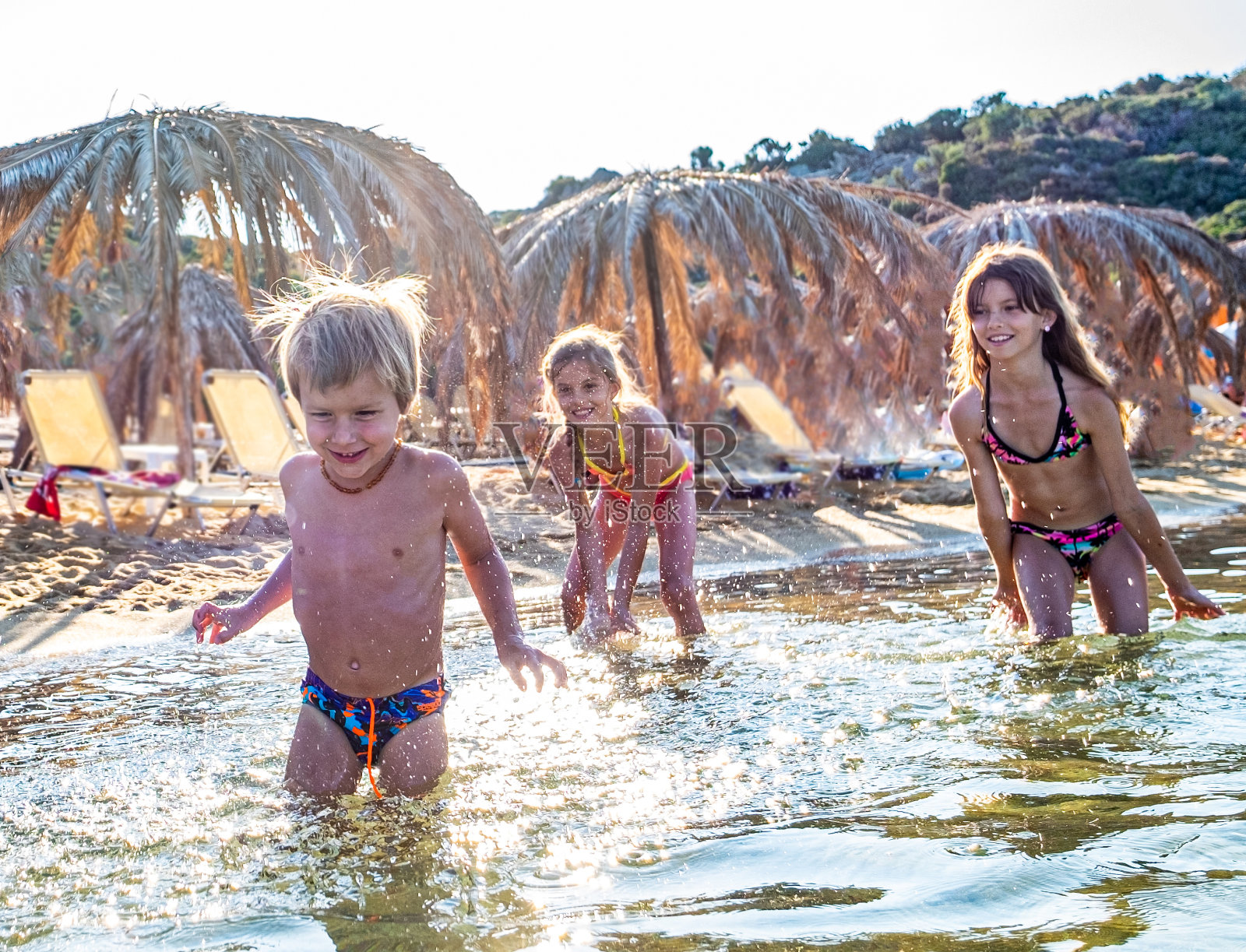 小男孩从这对姐妹身边跑开了照片摄影图片