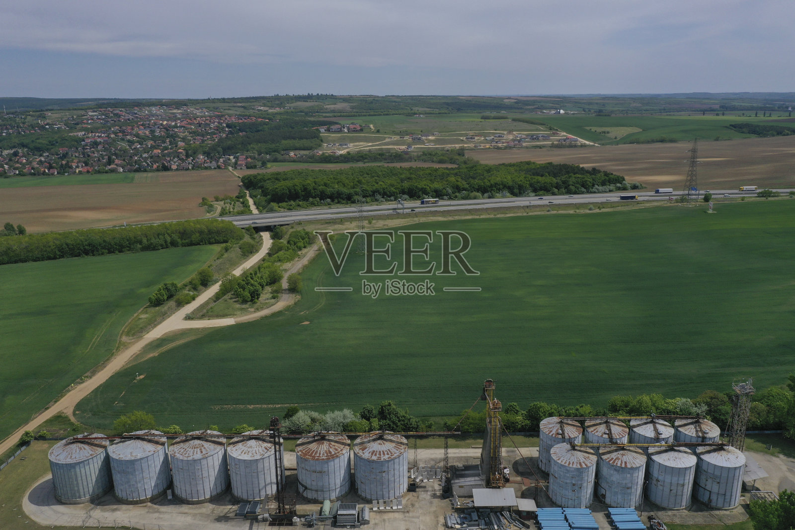 无人机鸟瞰图，农业筒仓，旁边的小麦或大麦田-工业升降机干燥机，建筑外部，储存和干燥谷物，小麦，玉米，大豆，向日葵。在欧洲照片摄影图片
