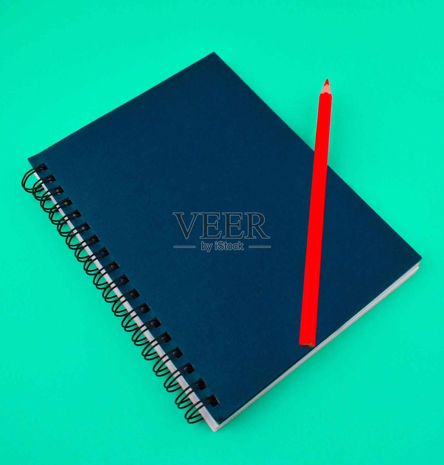 一只红色的木蜡笔放在一个蓝色的纸日记本上照片摄影图片