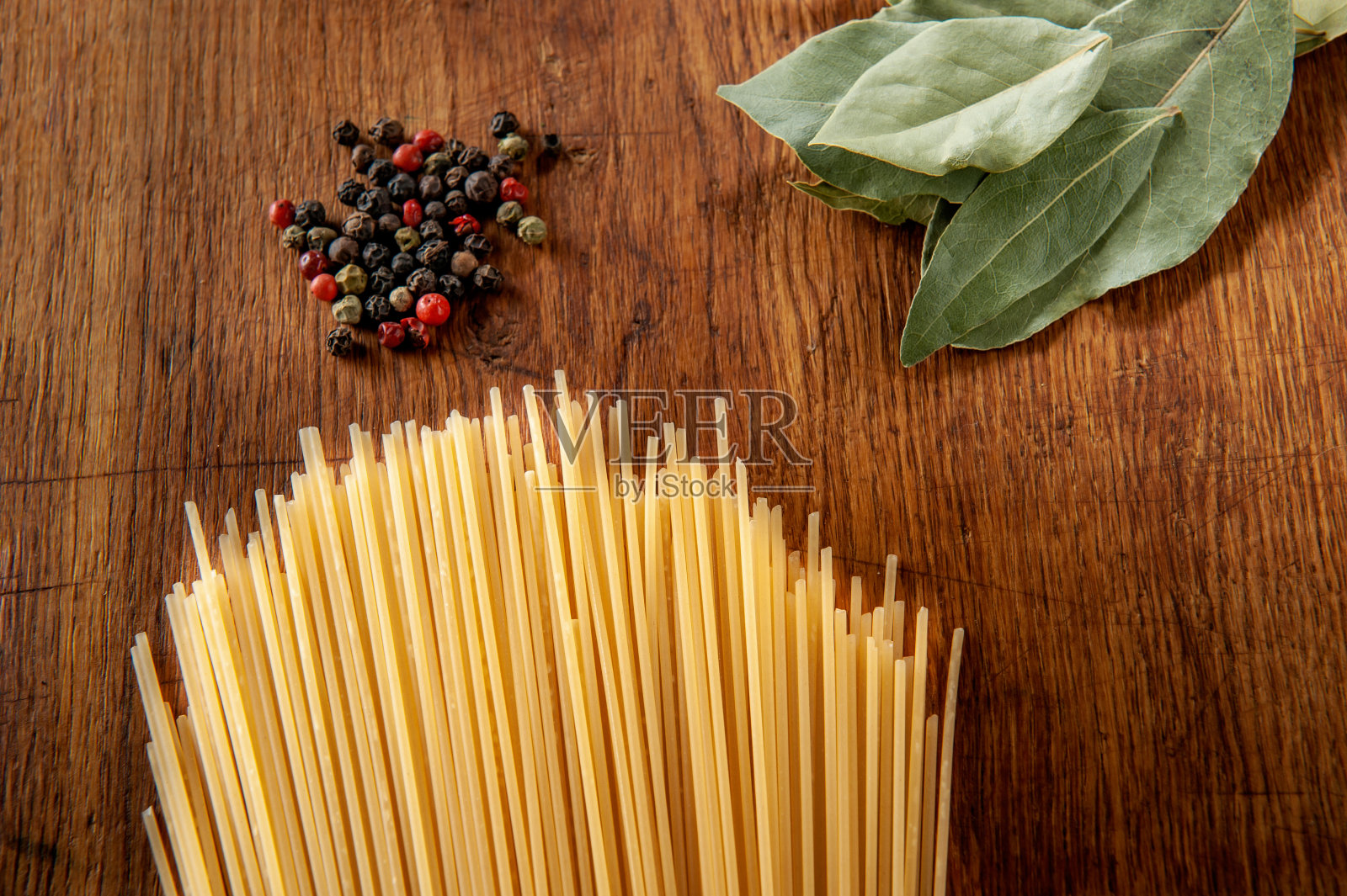 木桌上放着月桂叶和香料的意大利面，食物特写照片摄影图片