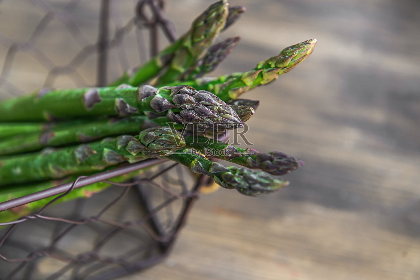 木桌上的篮子里放着一束新鲜芦笋。选择对焦的照片。照片摄影图片