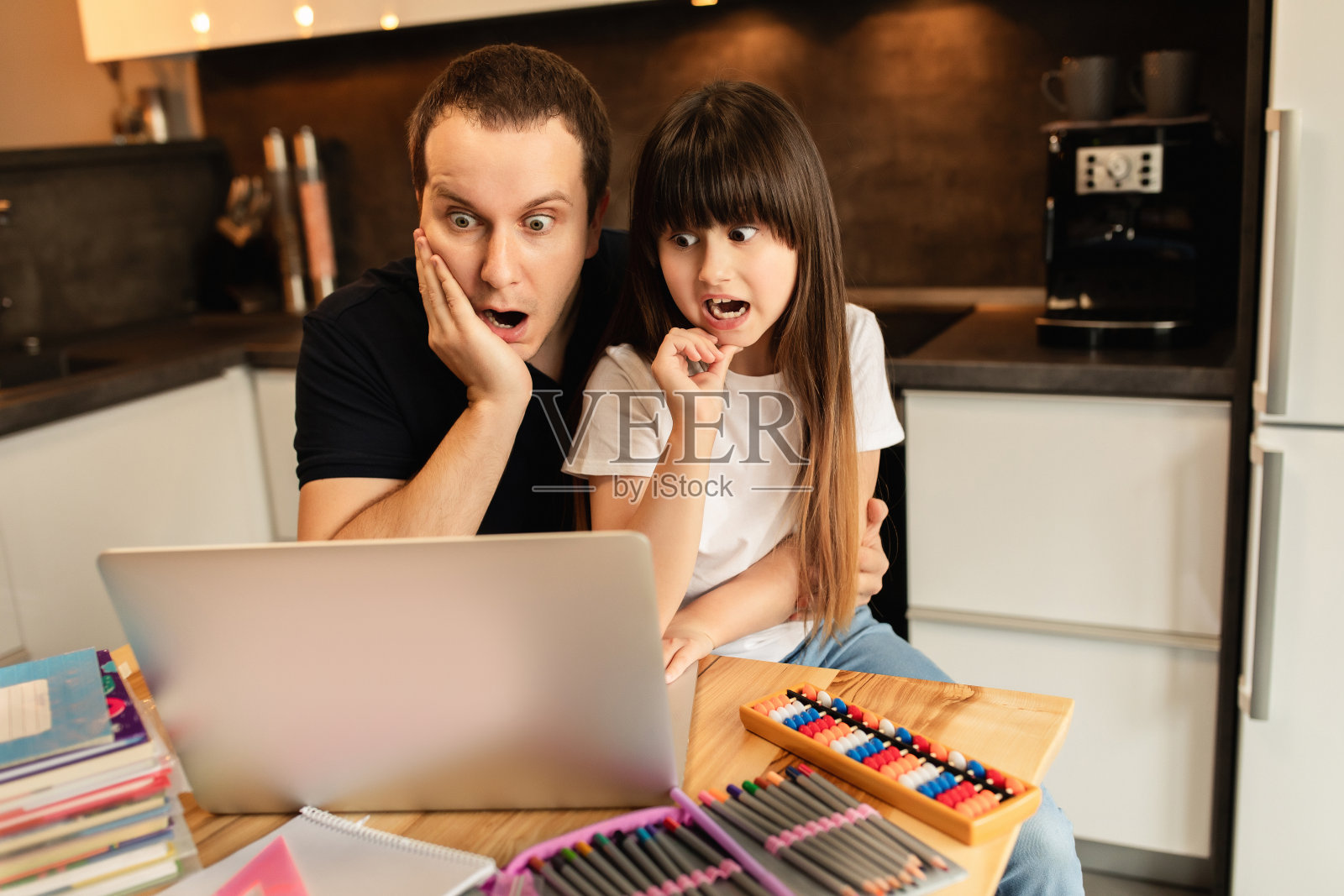 在线学习。一个女孩和她的父亲在家里用笔记本电脑看视频课。远程教育。全家人在一起的感觉照片摄影图片